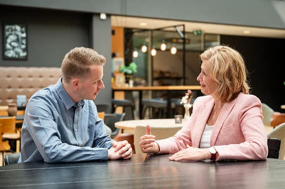 Leiderschapscoaching in een-op-een gesprek met coach Ine van den Heijkant aan een tafel in overleg